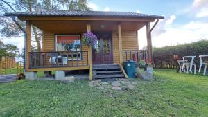 a small cabin with a porch and a table and chairs at Strazdiņi in Saraiķi