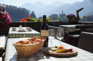 a table with a basket of bread and a bottle of wine at Gasthof La Pli Apartments in San Vigilio Di Marebbe