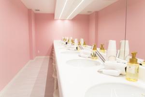 a row of sinks in a bathroom with pink walls at Akihabara Bay Hotel (Female Only) in Tokyo