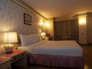 a hotel room with a large bed and a table at Florida Hotel in Hat Yai