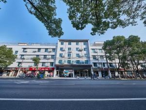 um grande edifício branco em uma rua da cidade em Magnotel Business Shanghai Minhang Wujing East China Normal University em Xangai