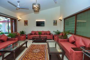 a living room with red couches and a tv at De Vivendi Farm- A Rural Luxury Farmhouse Getaway in Bahora