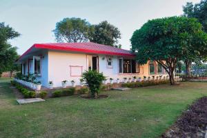a small white house with a red roof at De Vivendi Farm- A Rural Luxury Farmhouse Getaway in Bahora