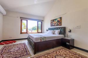 a bedroom with a large bed and a window at De Vivendi Farm- A Rural Luxury Farmhouse Getaway in Bahora +13 photos