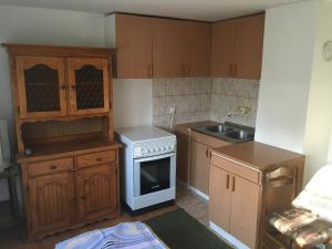 a kitchen with wooden cabinets and a white stove top oven at Guest House Nada in Soko Banja