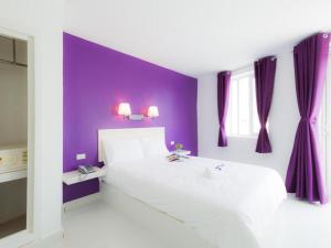 a bedroom with a white bed and purple walls at Hotel Zing Phnom Penh in Phnom Penh