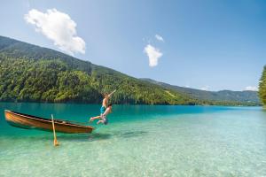 a boy jumping off of a boat in a lake at Pension Bergblick - Nebenhaus C in Neusach