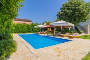 a pool with chairs and umbrellas next to a house at Villa Lavandis with Jacuzzi and 50m2 Pool in Donji Vinjani