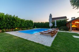 a backyard with a pool and a table and an umbrella at Villa Lavandis with Jacuzzi and 50m2 Pool in Donji Vinjani