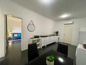 a white kitchen with a table and a counter at Private unit in Whitehaven Crescent in Cannonvale