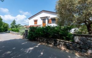 a white house with a stone wall next to a street at Holiday home Rozica by Villas Guide in Kras