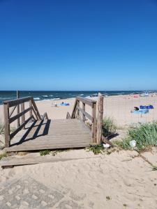 a wooden boardwalk on a beach with the ocean at Pokoje Gościnne u Marcina, Gästezimmer bei Martin in Mielno