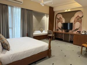 una camera da letto con un letto, una scrivania e una televisione di The Luxury Tiger at Lake Pichola a Udaipur