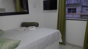 a bedroom with a bed and a window with a television at pousada do rei in Pedra de Guaratiba