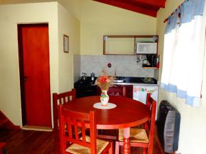 a kitchen with a wooden table with a vase of flowers on it at Cabañas Rancho Unelen in Colón