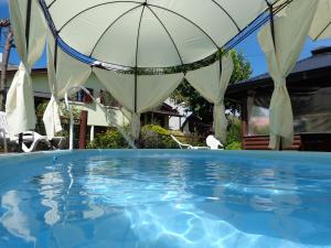 an umbrella over a swimming pool with a house at Cabañas Rancho Unelen in Colón