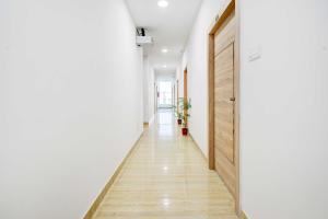 a hallway with white walls and a wooden door at Townhouse Oak LB Nagar Metro Station in Hyderabad