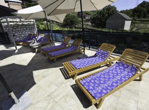 a group of lounge chairs with umbrellas on a patio at Holiday Home Marana in Drniš +3 photos