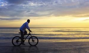 un hombre montando una bicicleta en la playa en Apartamentos Creoli, en Ayamonte