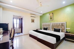 a bedroom with a bed and a desk and a television at Collection O CMR Mall Gajuwaka in Visakhapatnam