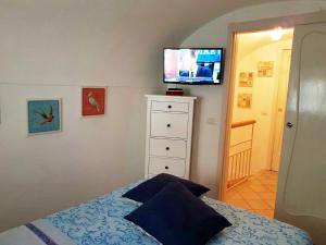 a bedroom with a bed with a television on the wall at Casa Romanzi in Capri