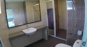a bathroom with a sink and a shower and a toilet at HOTEL KAWAN BIDOR in Sungkai