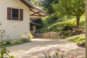 a house with a stone wall next to a road at Le Moulin paradis entre Genève&Annecy in Viry