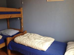 a bedroom with two bunk beds and a blue bed at Sotra Rorbusenter in Kåravika