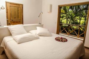 a bedroom with a white bed with a window at Villa Ixora - Ocean Front in Las Galeras