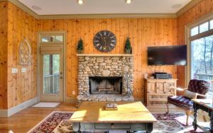 a living room with a stone fireplace and a clock at Paradise Retreat - Luxury chalet on Lake Disharoon with foosball in Marblehill