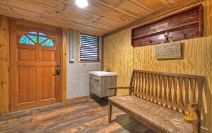 eine Holzbank in einem Zimmer mit Tür in der Unterkunft Knotty Creek Retreat - Creek Access, Outdoor Firepit + Hot Tub with Creek Views! in Morganton + 68 Fotos