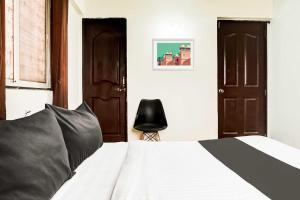 Un dormitorio con una cama y una silla negra. en Collection O Viman Nagar Kendriya Vidyalaya, en Pune