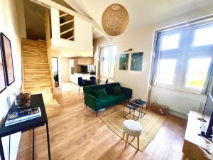 a living room with a green couch and a staircase at Le Cocon du Mont'Anay in Montanay