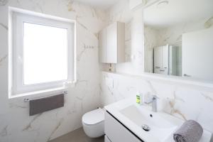 a white bathroom with a sink and a window at Modern Home Suites in Domžale +11 photos