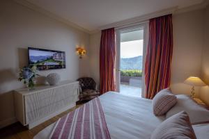 卢加诺Resort Collina d'Oro - Hotel, Residence & Spa的一间卧室设有一张带电视和窗户的床。