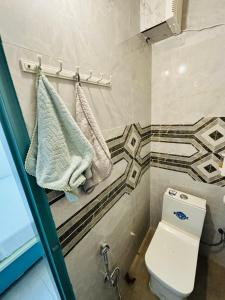 a bathroom with a toilet and towels on a rack at Hotel Minar in Rohtak