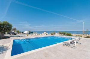 a swimming pool with two chairs and the ocean at Apartments Ruzmarin in Lun