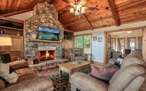 a living room with couches and a stone fireplace at Wine Down Cottage - Mountain Views Sip Wine Fireside Watch Netflix Play Golf in Jasper