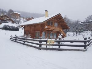 a log cabin in the snow with a fence at Chalet Risoul jusqu'à 8 personnes in Risoul