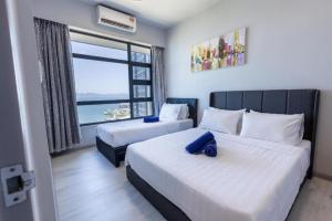 a bedroom with two beds with a view of the ocean at Capital O 90998 Margo Home in Kampong Layan