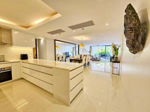 a kitchen with white cabinets and a dining room at 2 Bedrooms Apartment pool access in Ban Lum Fuang