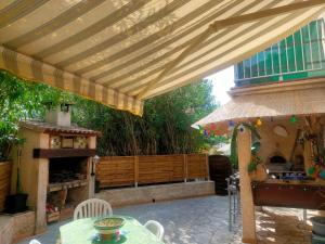 a patio with awning and a table and a fireplace at Maison Villa d'exception meublée piscine privée & cheminée a 2min plage et commerces in Marseillan