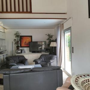 a living room with two leather couches and a tv at Maison Villa d'exception meublée piscine privée & cheminée a 2min plage et commerces in Marseillan