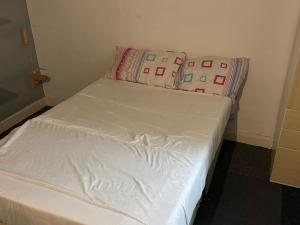 a small bed with white sheets and two pillows at Pdmdecor House in Hunslet