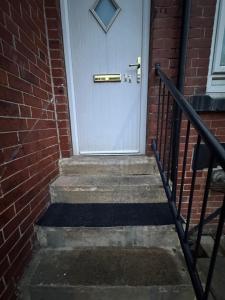 a white front door of a brick house with stairs at Pdmdecor House in Hunslet