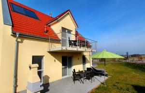 a house with a red roof with a table and an umbrella at Lontargos OG Wohnung in Göhren-Lebbin