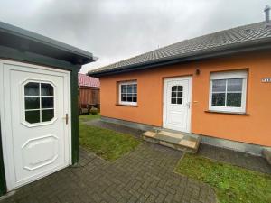 a orange house with a white door and windows at Ferienwohnung Bunte Wiese in Parchtitz