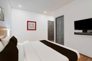 a white bedroom with a bed and a flat screen tv at Townhouse Oak Gomti Nagar Healthcity Vistaar in Lucknow +25 photos
