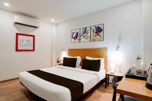 a bedroom with a large white bed and a desk at Townhouse Oak Gomti Nagar Healthcity Vistaar in Lucknow