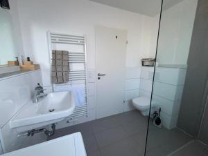 a white bathroom with a sink and a toilet at 3 bedroom apartment in Leverkusen incl parking-near Messe Deutz-Lanxessarena-Bayarena in Leverkusen +32 photos